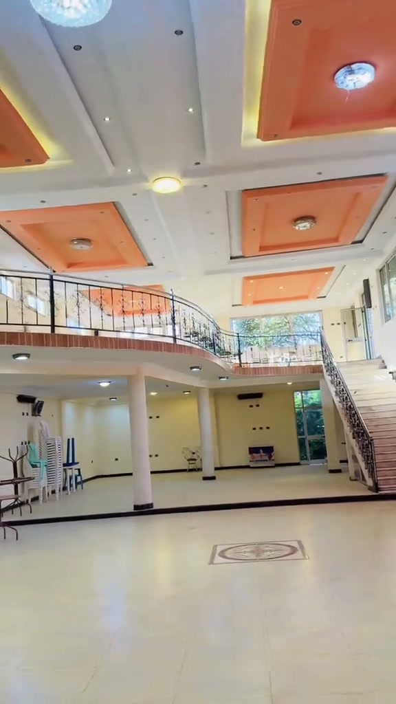 Curved upper mezzanine balcony and wrought-iron staircase overlooking Gibe Hotel event hall