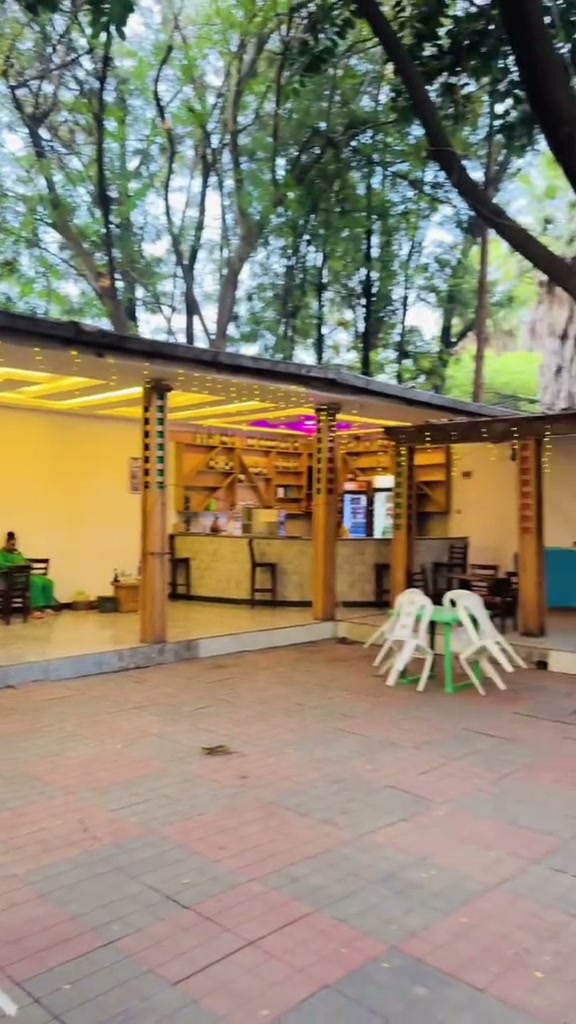 Covered outdoor veranda with stocked bar counter, warm cove lighting, and patio dining tables